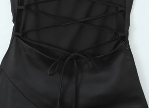 Close-up of black satin dress back featuring lace-up straps and an invisible zipper