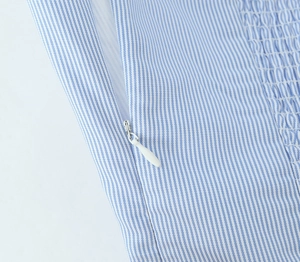 Detail view of the hidden zipper and smocking on blue and white striped summer dress