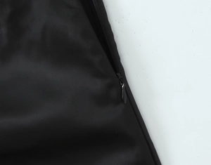 Detail of the invisible zipper and silky black satin fabric of the backless dress