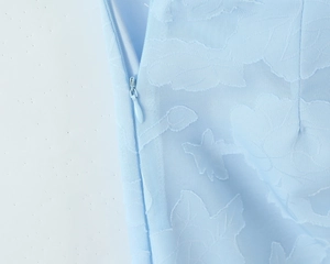 Detail view of light blue dress showing floral jacquard fabric and invisible side zipper