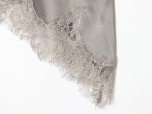 Close-up of grey satin camisole featuring intricate eyelash lace trim and silky texture