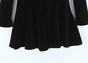 Detailed view of black velvet dress hem showing soft texture and pleated wave drape