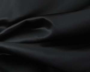 Detailed view of luxury black satin fabric texture with elegant drapes and smooth silk luster