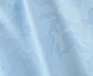 Macro detail of light blue jacquard fabric featuring embossed 3D rose floral patterns