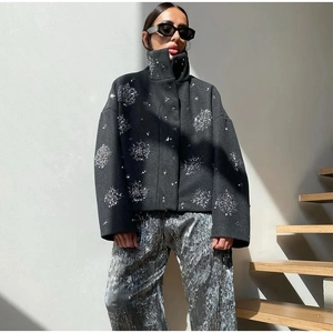 Detailed close-up of silver sequin snowflake embroidery on a black winter jacket