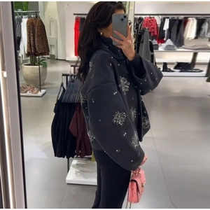 Detailed side view of black oversized jacket featuring sparkling silver sequin snowflake patterns