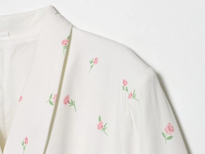 Gros plan de l'imprimé floral sur blazer blanc avec fleurs roses et coutures soignées