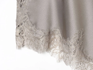 Detailed view of taupe silk fabric with exquisite eyelash lace trim on the hemline