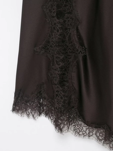 Detail shot of elegant black satin hem with delicate eyelash lace trim for women