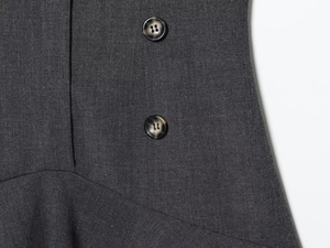 Detail of dark gray twill fabric with marble pattern buttons and fine stitching