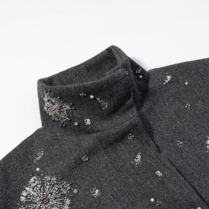 Close-up of snowflake sequins and silver beadwork on a dark grey stand collar jacket