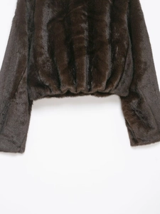 Detail of dark brown faux fur jacket showing the plush texture and elasticized hem