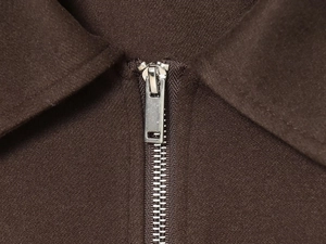 Detailed macro view of high-quality silver metal zipper on a dark brown jacket