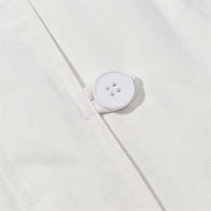 Detailed close-up of a white four-hole button and twill cotton fabric on a hooded jacket