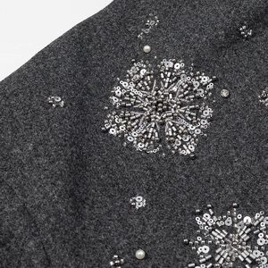 Macro view of sequin embroidery and white pearls on dark grey wool jacket