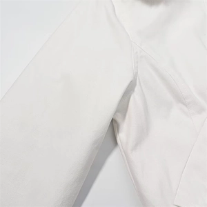 Detailed close-up of white cotton jacket texture with soft faux fur trim on the collar