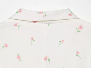 Gros plan du revers à motif floral sur blazer blanc montrant la texture du tissu