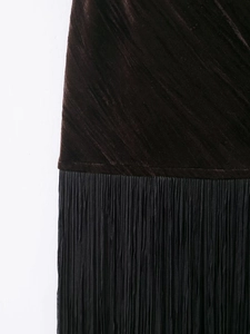 Détail du tissu en velours avec des franges noires denses sur une robe marron