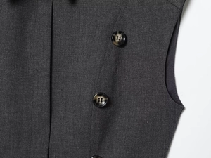 Detail of dark grey twill dress with marbled resin buttons and precise sleeve tailoring