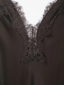 Detail of delicate eyelash lace trim on a silky satin V-neck dress bodice