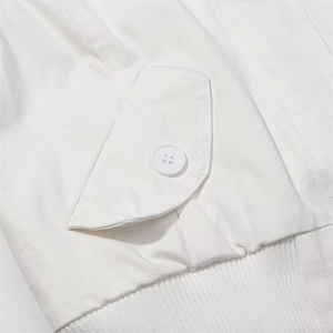 Detail view of white casual cotton jacket showing flap pocket with button and ribbed hemline