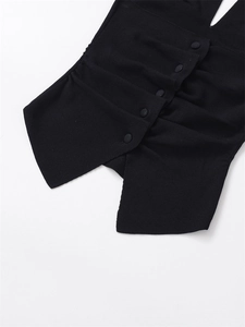 Detail of black knit top featuring asymmetric pleated design and refined fabric buttons