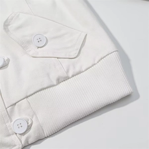 Detailed close-up of white cotton jacket waist with buttoned pocket and ribbed hem