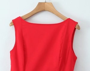 Detail of red sleeveless off-shoulder dress featuring smooth fabric on a wooden hanger
