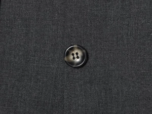 Detailed macro view of high-quality resin marble button on dark grey woven dress fabric