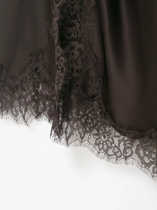 Macro detail of satin dress fabric featuring delicate black eyelash lace trim