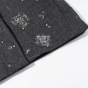 Detailed view of dark grey wool jacket with silver sequins and white faux pearl embroidery