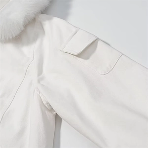Detail of white winter parka featuring plush faux fur collar and utility sleeve pocket