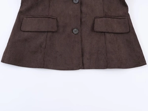 Close-up of brown corduroy blazer showing ribbed texture, black buttons and flap pockets