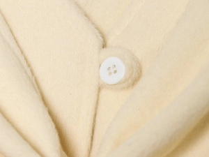 Close-up of beige wool coat featuring fluffy texture and white resin button detail