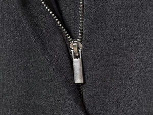 Close-up of high-quality silver metal zipper and twill fabric texture on a black dress