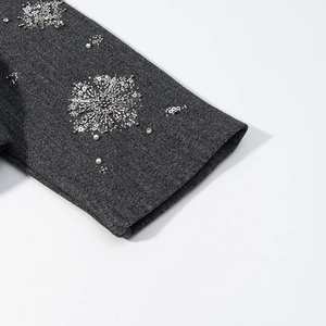Detailed view of dark grey jacket cuff with silver sequins and pearl floral embroidery