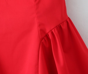 Detailed macro view of the red dress showing pleated ruffles and fine stitching craft