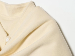Detailed close-up of cream wool coat fabric texture and elegant white round button