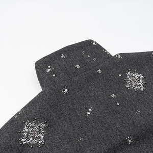 Close-up of dark grey wool jacket with hand-sewn silver sequins and white pearls