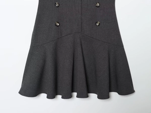 Detailed view of charcoal grey mini dress featuring vintage buttons and ruffled hemline