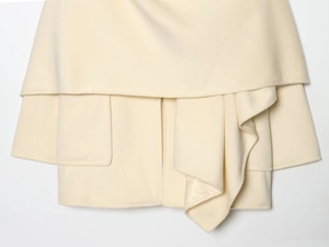 Detail of cream woolen coat showing pocket structure and textured fabric finish