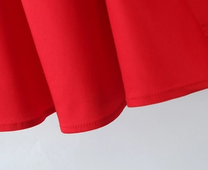 Detail of red dress hem with precise stitching on high-quality woven fabric texture