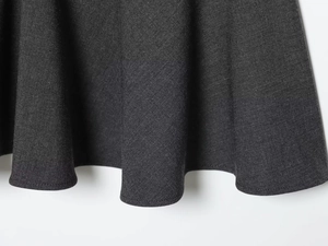 Macro detail of charcoal grey dress hem showing dense fabric texture and neat stitching