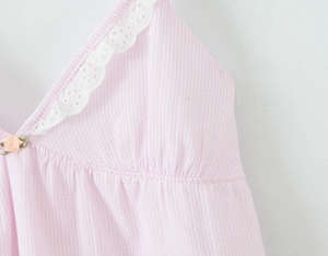 Detail von rosa gestreiftem Stoff mit weißer Spitzenkante und kleiner Blumenverzierung