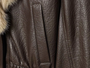 Détail de la veste en similicuir marron avec poche verticale et col en fausse fourrure