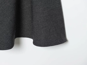 Close-up of the dark grey woven hem with precision stitching on a sleeveless dress