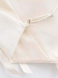 Close-up of white fabric texture and silver metal hook on a backless halter top