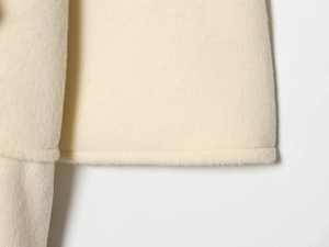 Detailed close-up of cream wool blend coat hem showing high-quality stitching and texture