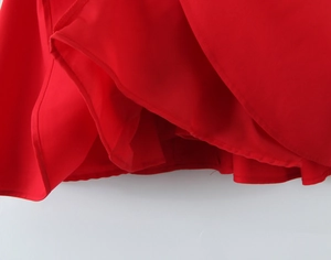 Detail shot of the layered hem on a red evening dress showing soft draping fabric