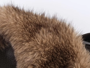Détail de la bordure en fausse fourrure marron et du cuir noir grainé sur une veste en PU